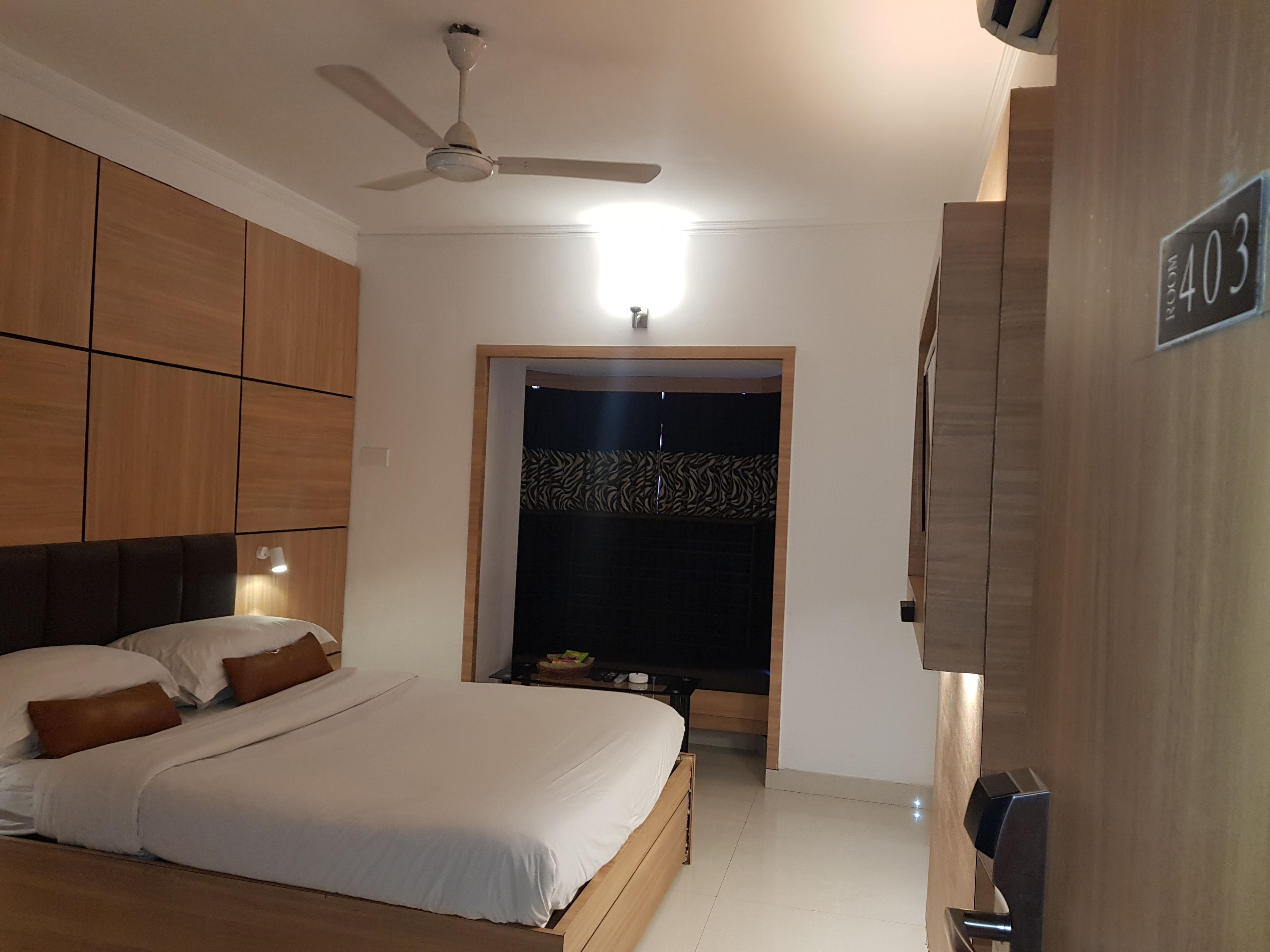 A bedroom with a bed, a ceiling fan, a nightstand, and a wardrobe.