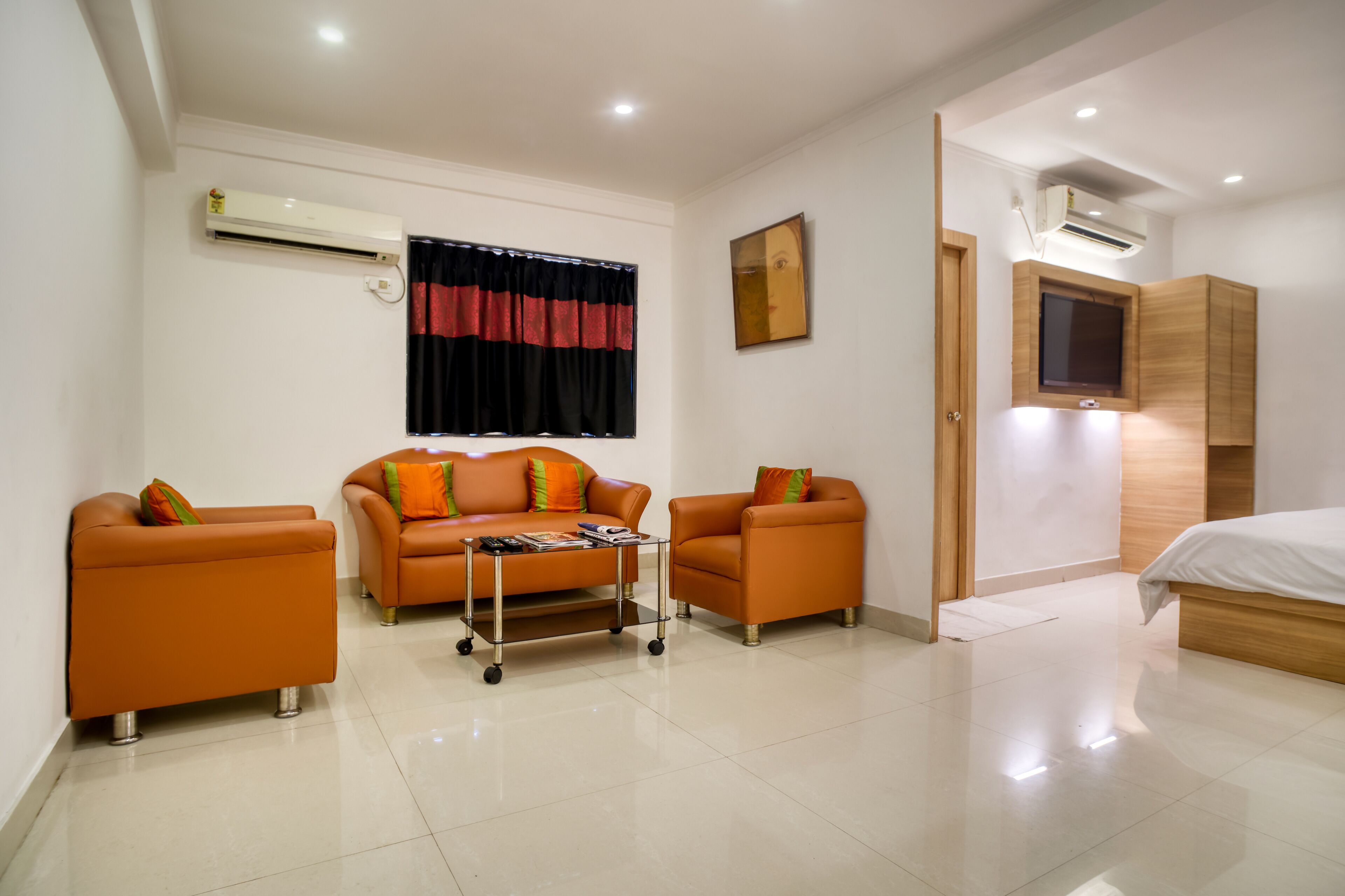 A modern hotel room with a sofa set, a small table, a TV, and a bed.