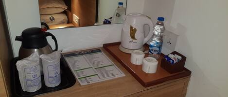 A hotel room's minibar area with a coffee maker, bottled water, and a menu.