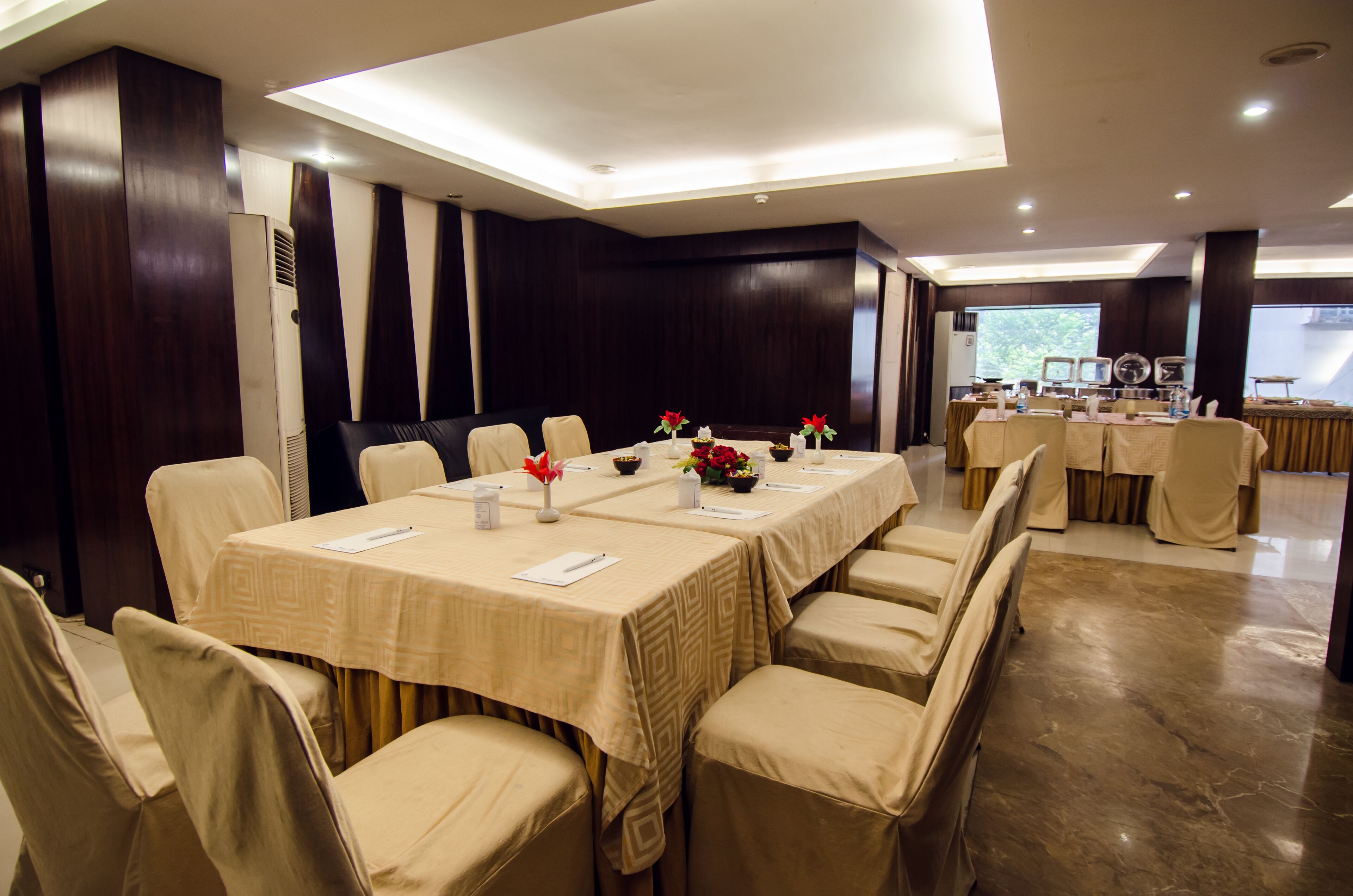 A conference room with multiple tables and chairs, equipped with nameplates, water bottles, and floral centerpieces.