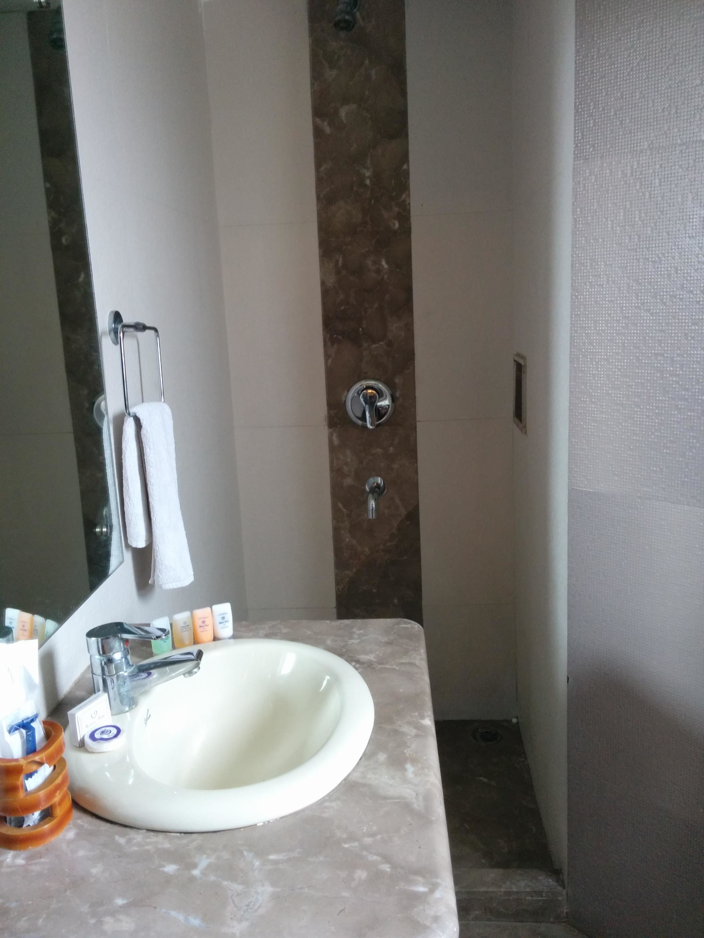 A bathroom with a marble sink, a mirror, a towel rack, and toiletries.