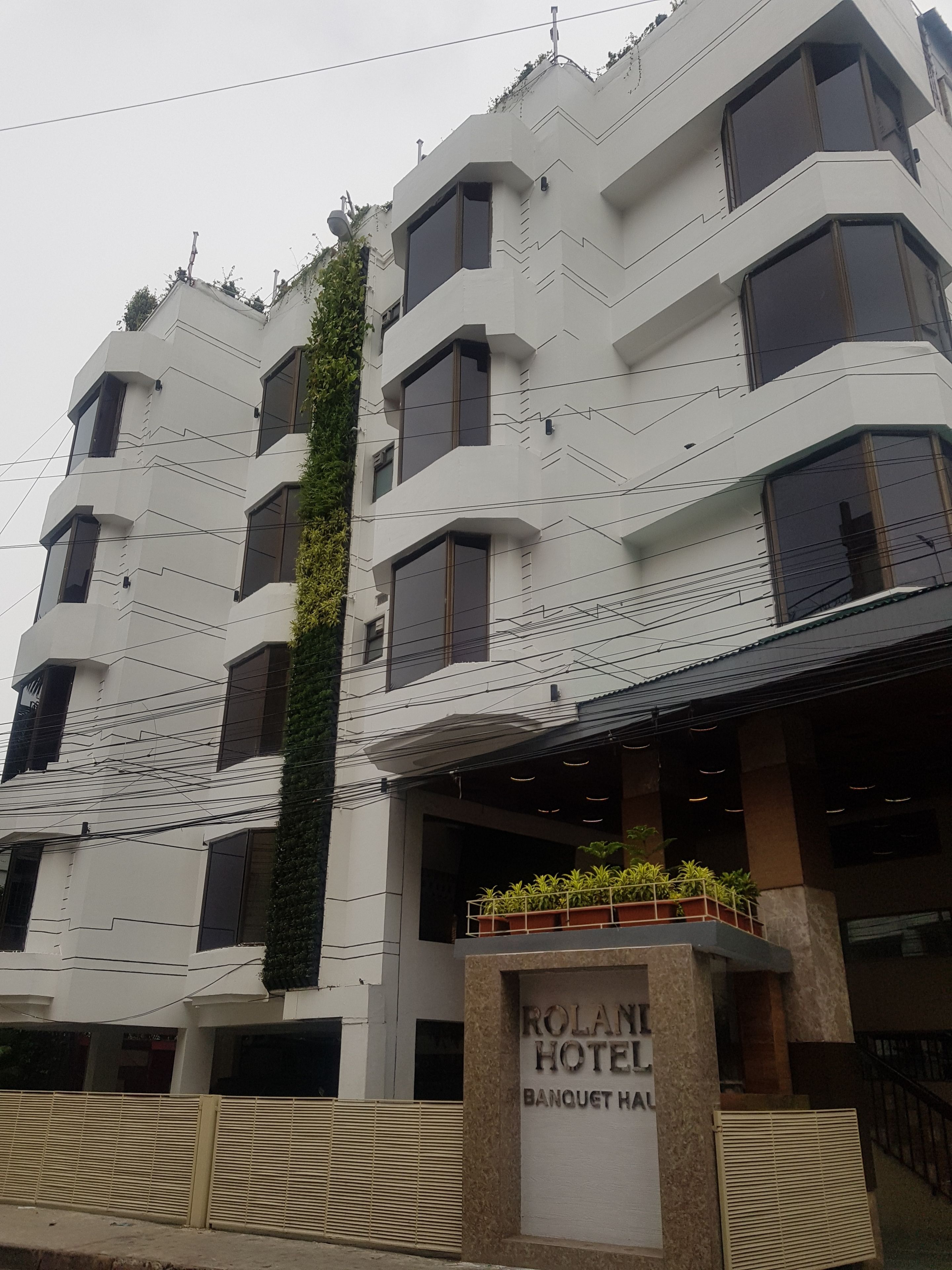 A modern hotel building with a sign reading "ROLAN HOTEL BANQUET HAL."