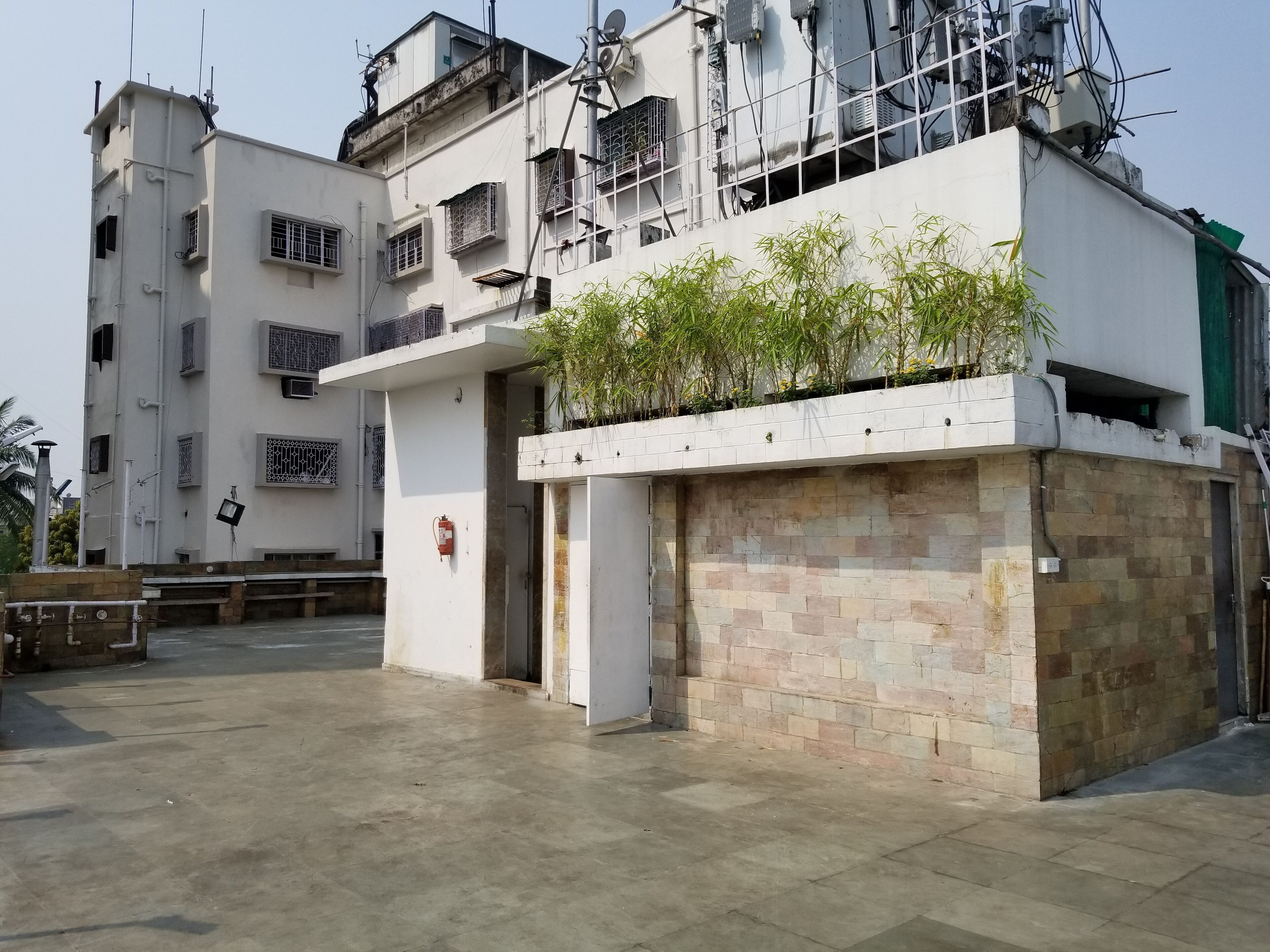 A multi-story residential building with a flat roof, air conditioning units, and a gated entrance.