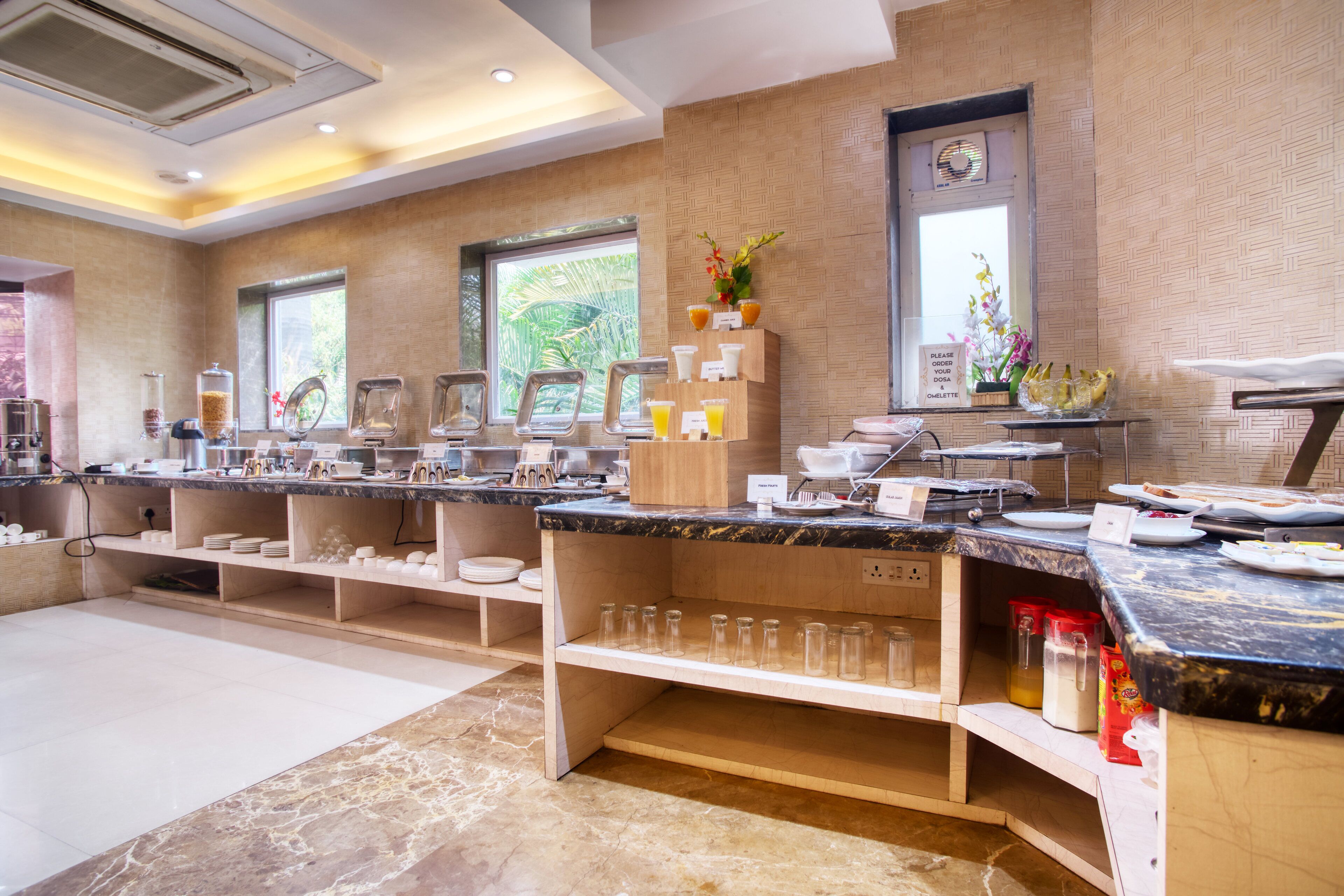 A modern breakfast bar with marble countertops, glassware, and a variety of breakfast items.