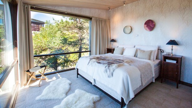 A bedroom with a large bed, a balcony, and a view of trees. - Ruka Peak (Kuusamo)