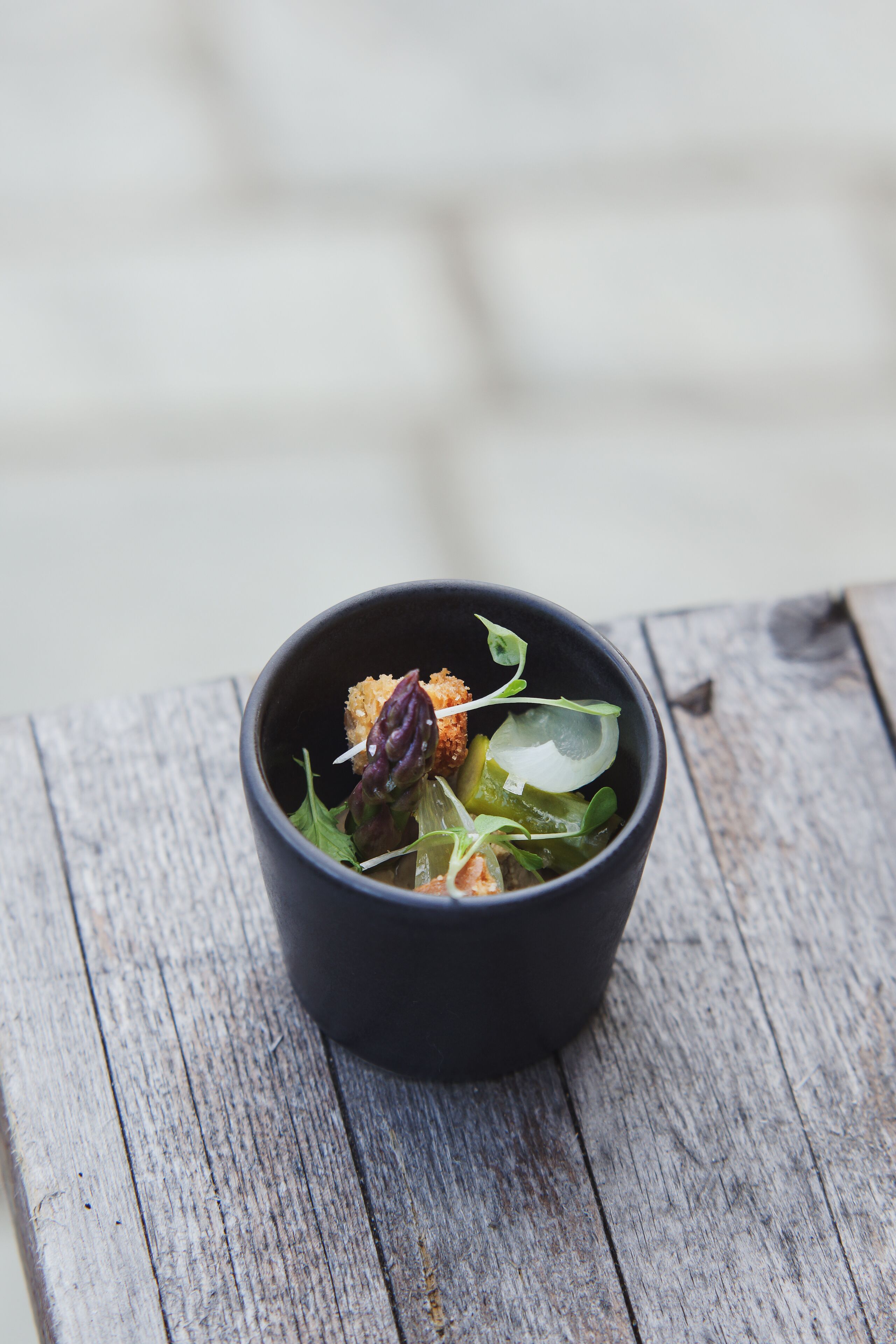 A black bowl of salad on a rustic wooden table.