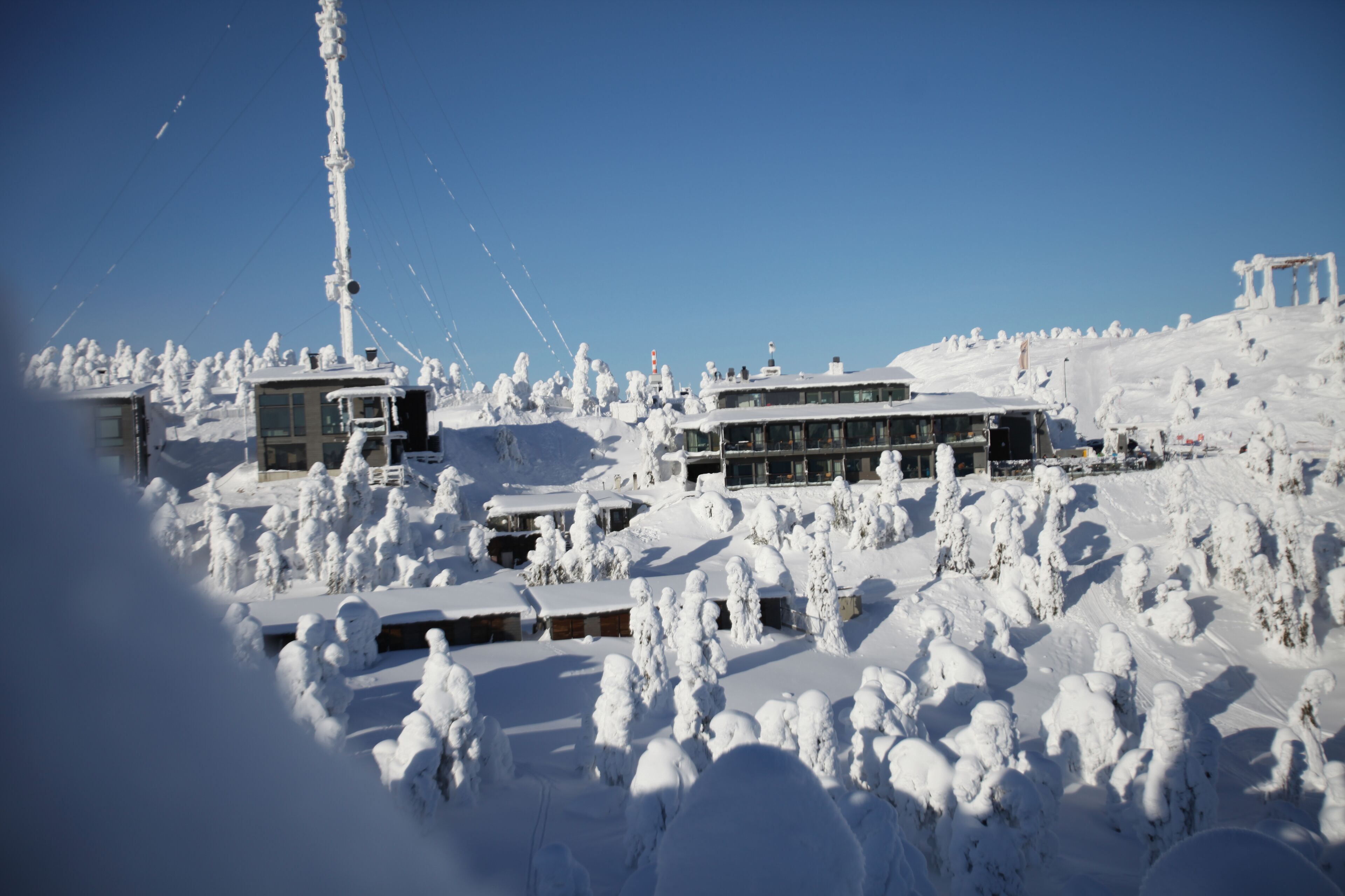 Un hotel cubierto de nieve con varias construcciones y un telesilla al fondo.