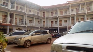 A multi-story building with balconies, parked cars, and a visible entrance. - Kirigime Guest House (Kabale)