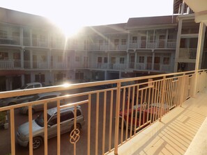 Un edificio de varios pisos con balcones, un estacionamiento con coches y una vista despejada del entorno.