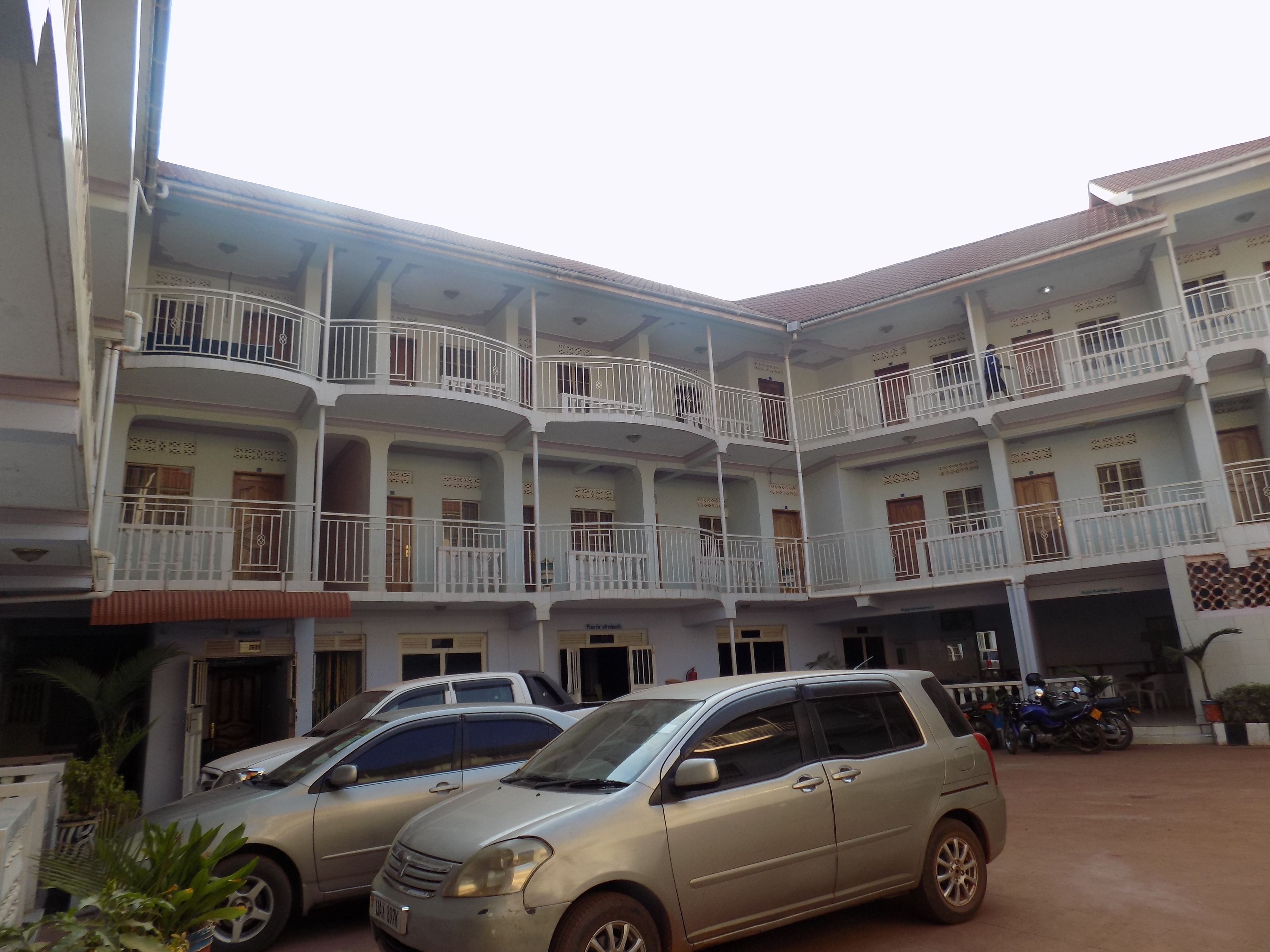A multi-story building with balconies and parked cars.