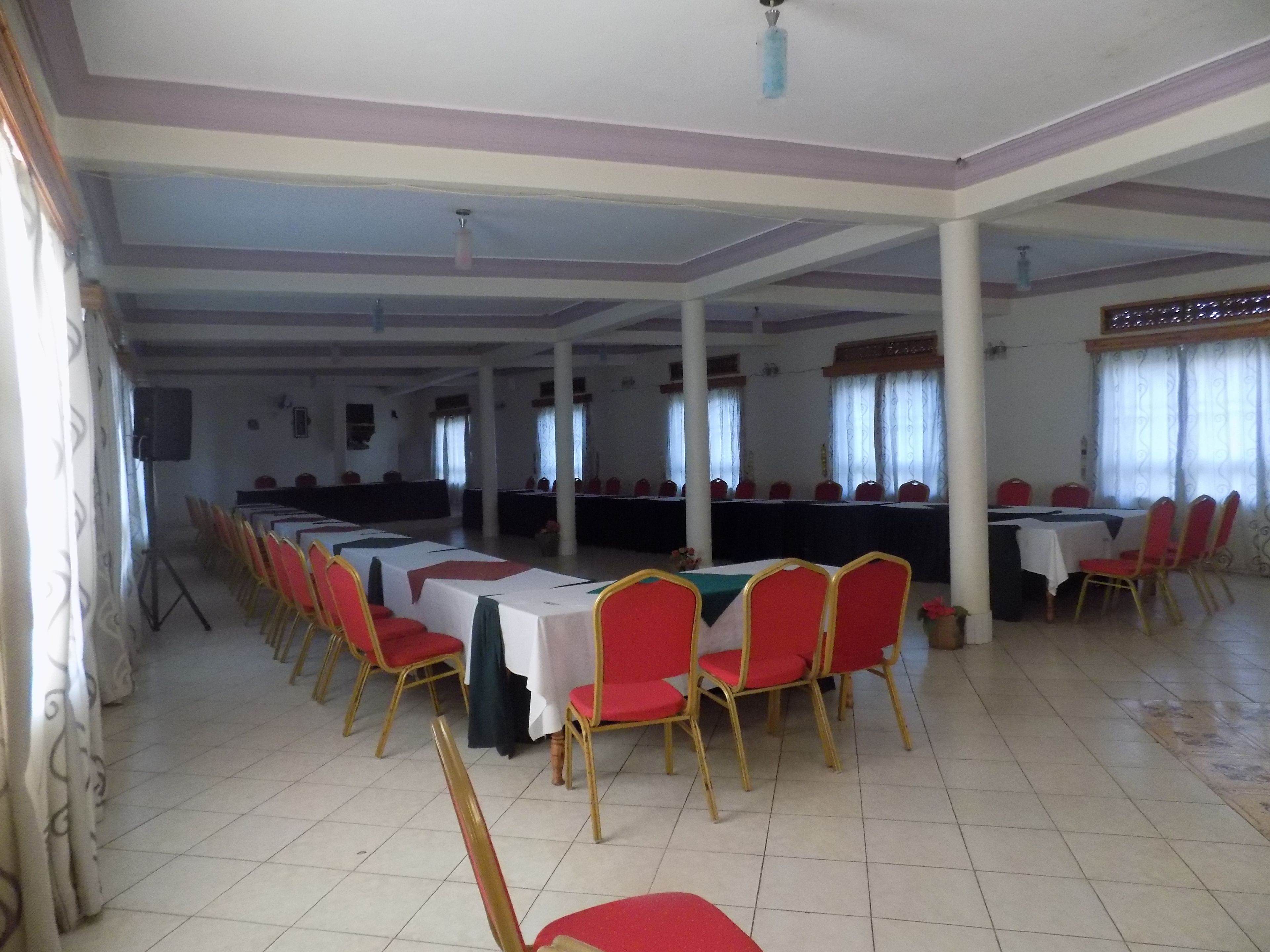 Un'ampia sala con numerosi tavoli e sedie disposti in file.