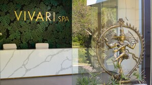 A reception desk with a 'VIVARI SPA' sign, a decorative statue, and a lush green leaf-patterned wall.