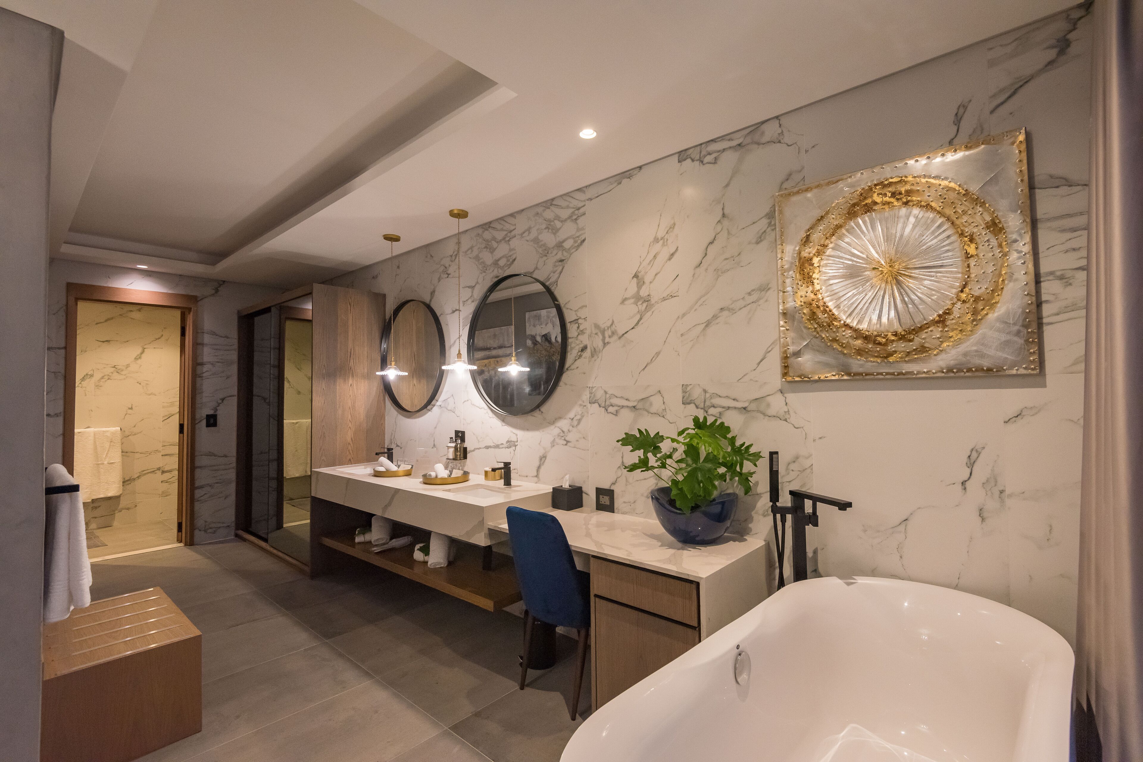 Une salle de bain moderne avec un mur en marbre, une baignoire sur pieds, un meuble-lavabo et un miroir.
