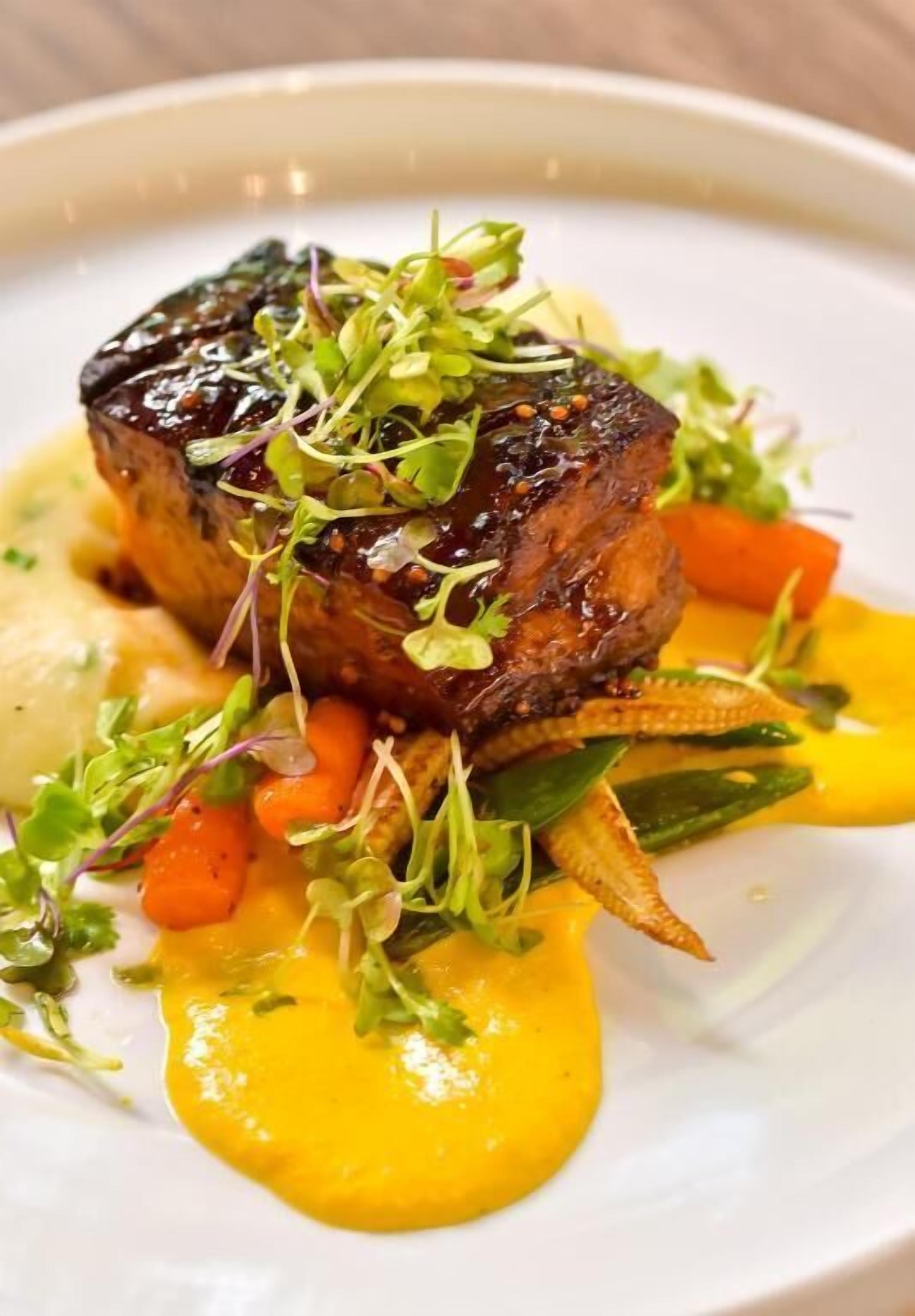 Un plato con carne, verduras y salsa amarilla.