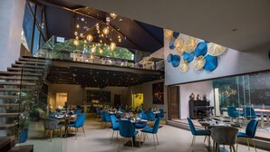 A modern dining area with blue chairs and a glass staircase.