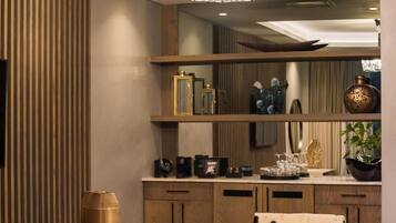 A modern interior with a round table, two chairs, a chandelier, wooden cabinets, and decorative items on shelves.