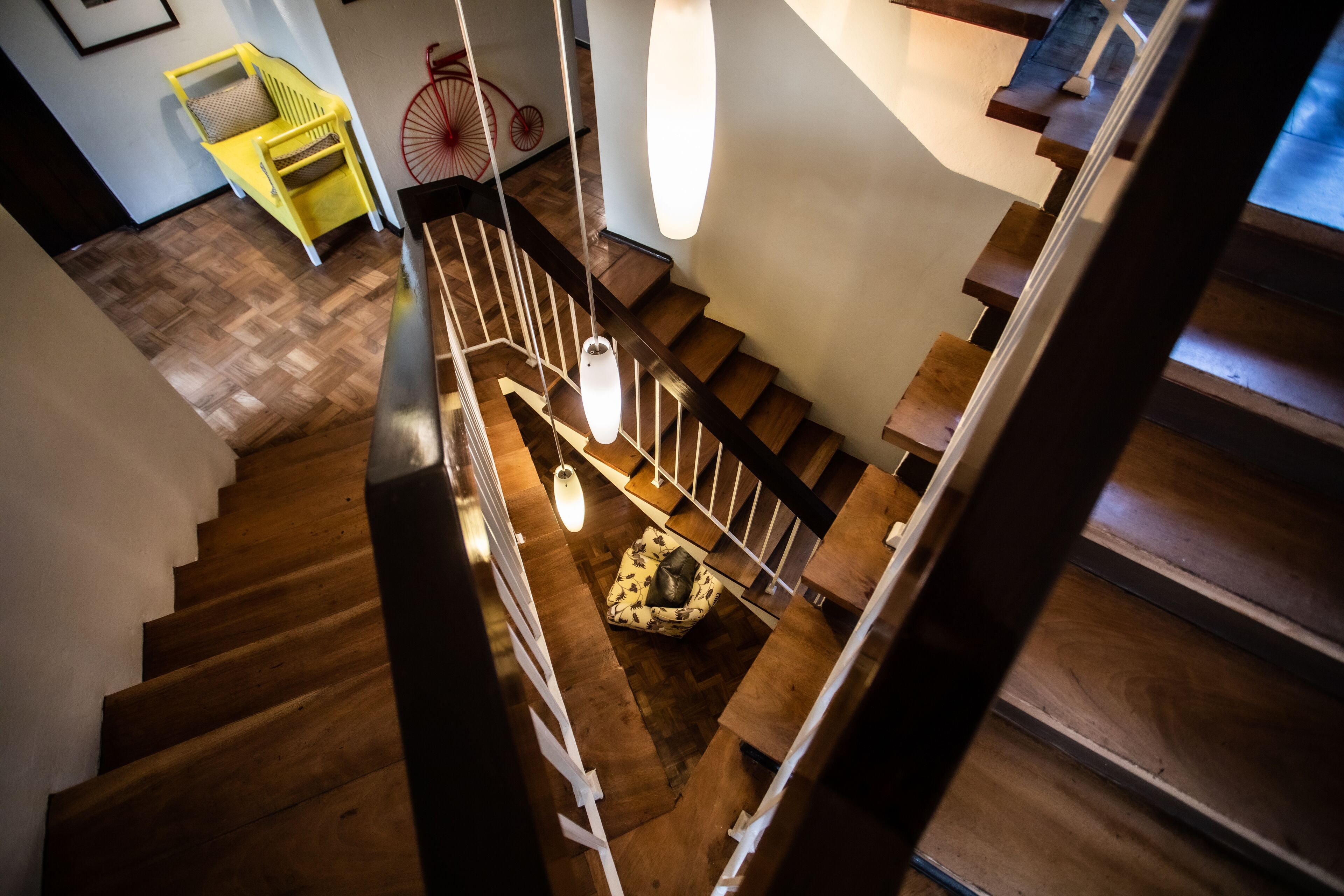Una escalera de madera con barandillas blancas y un candelabro colgante.