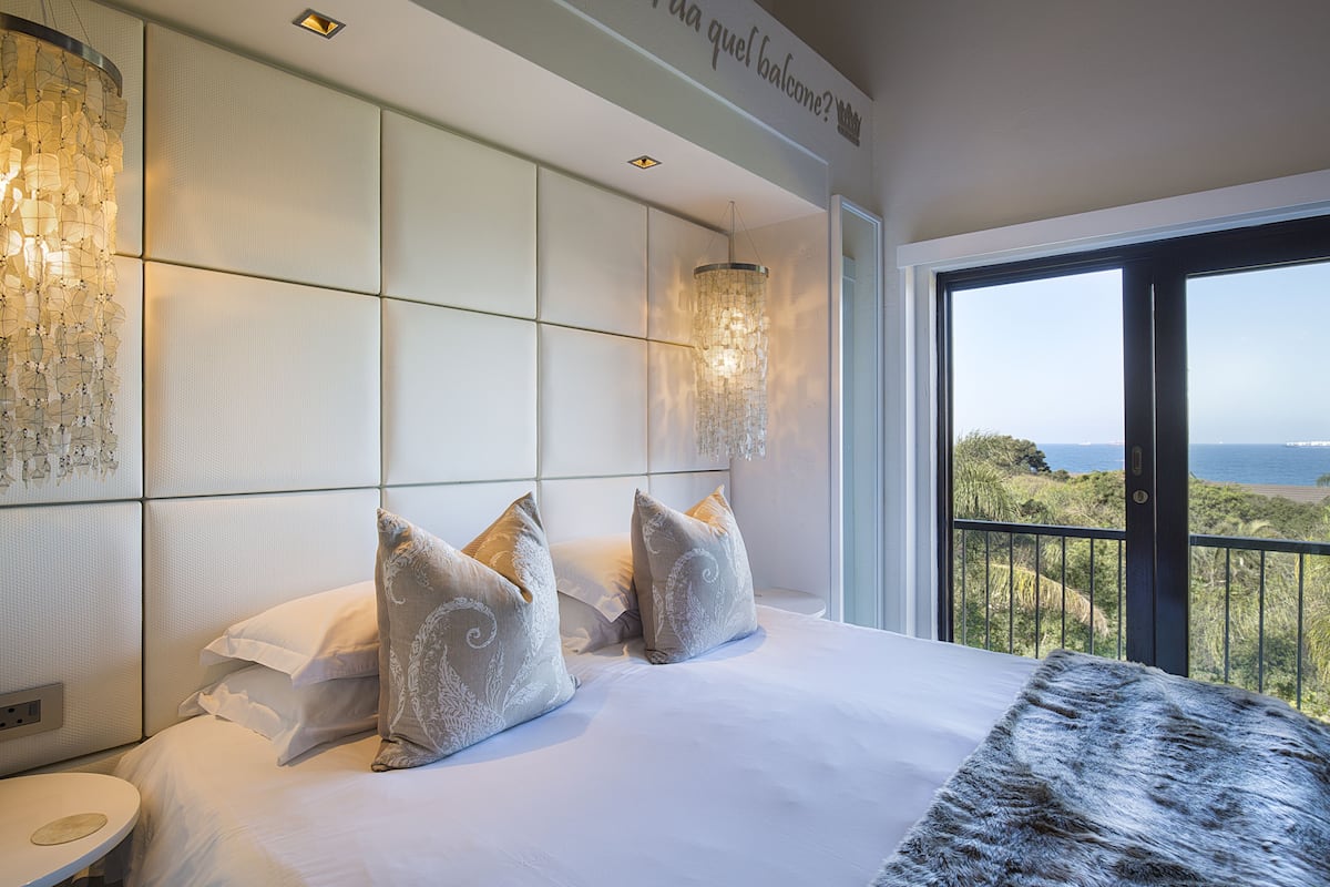A hotel room with a large bed, a view of the sea, and a balcony.