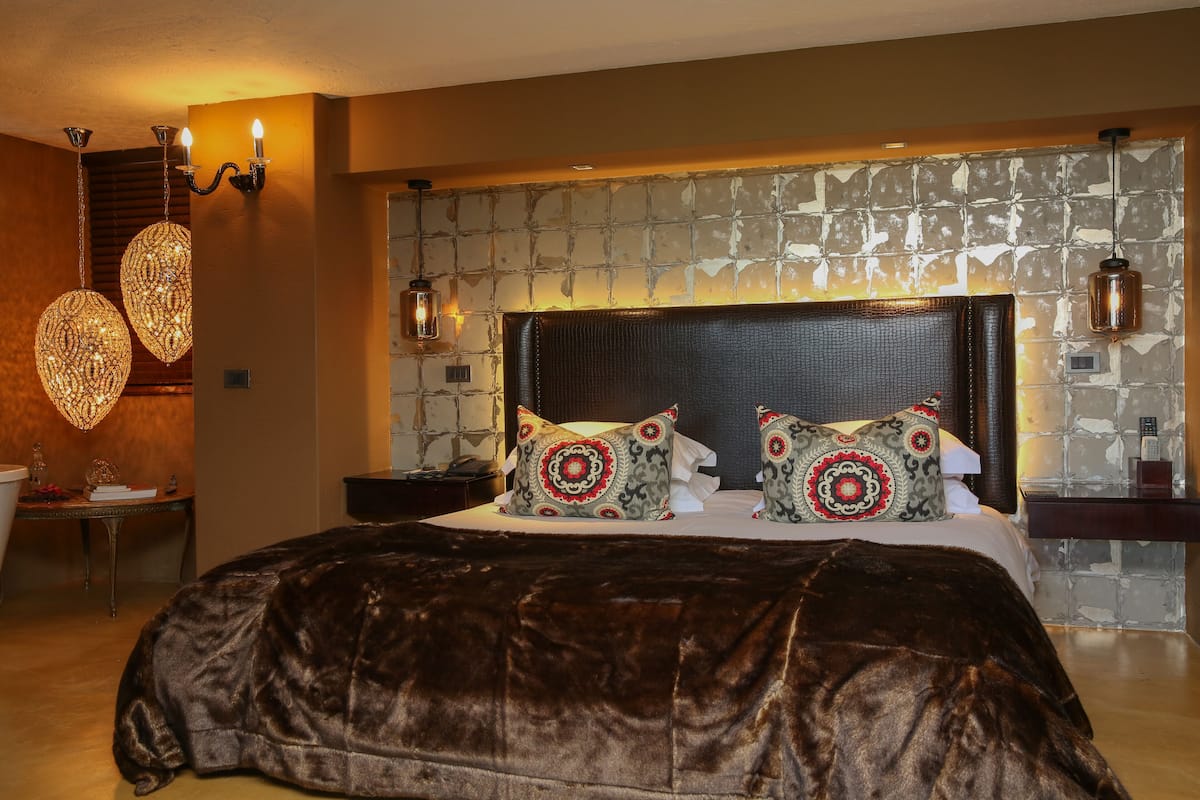 A large bed with a dark headboard, two decorative pillows, and a textured wall behind it.
