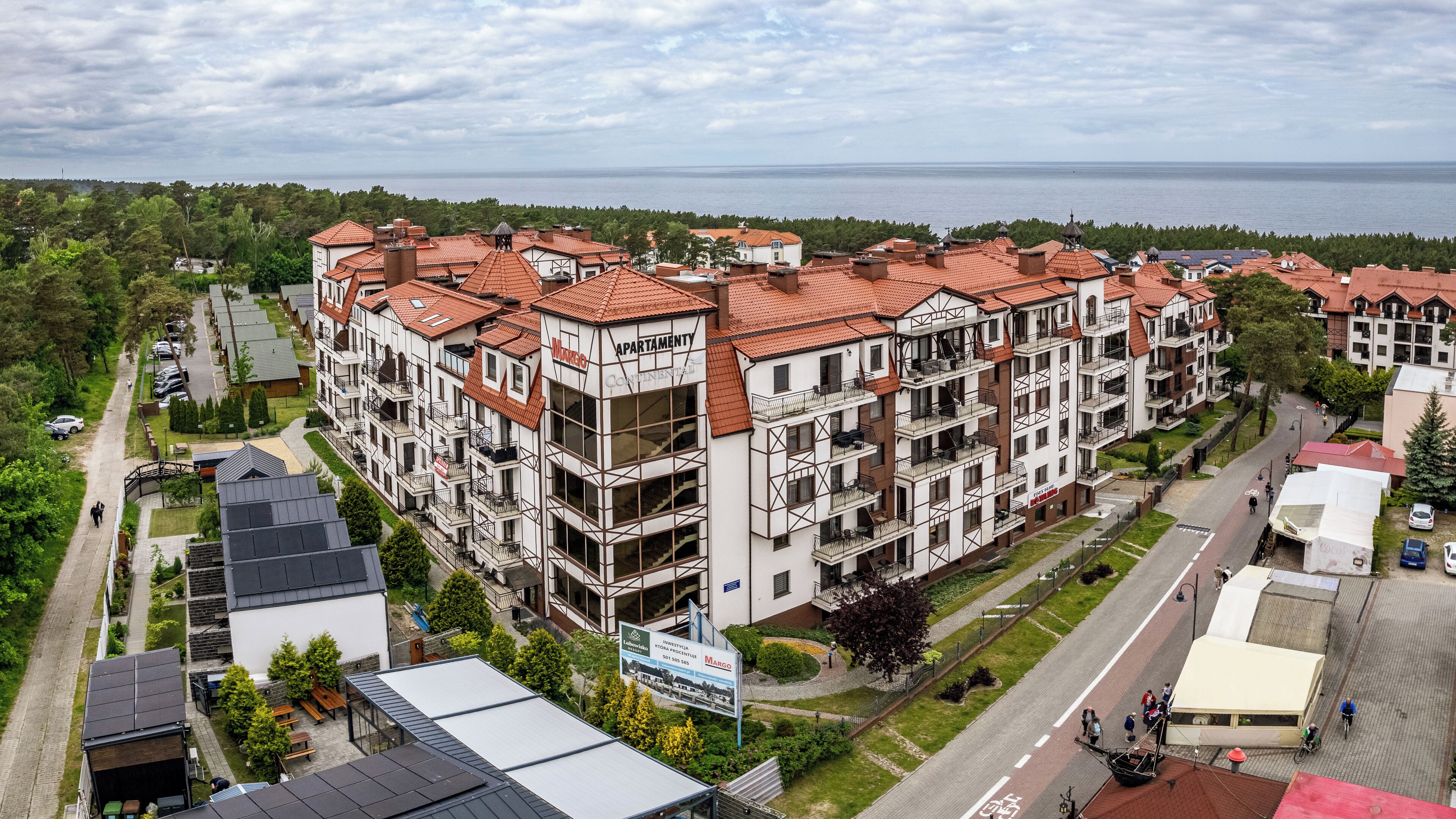 Un immeuble d’appartements à plusieurs étages, avec un toit recouvert de tuiles rouges, des balcons et une vue sur la mer.