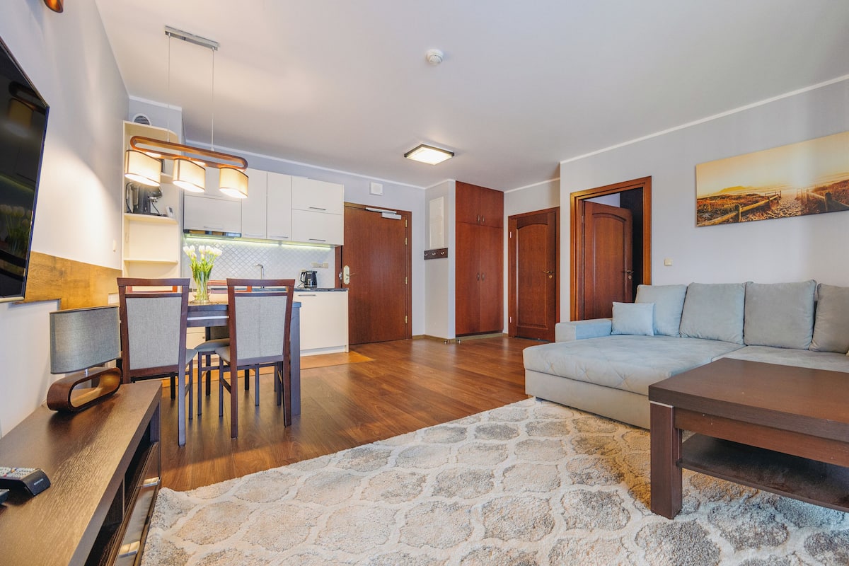 Una sala de estar moderna con sofá, mesa de centro y comedor con sillas y una mesa.