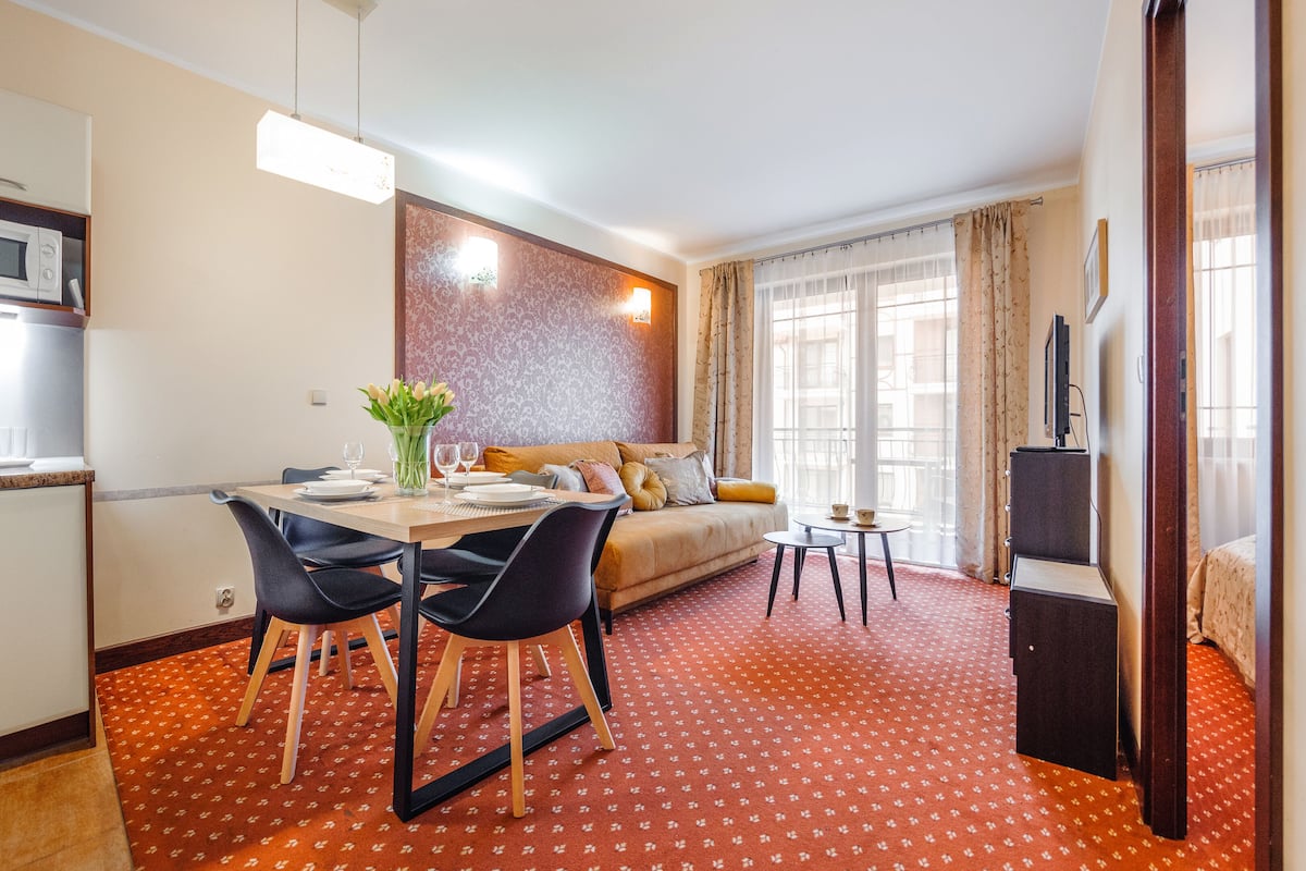 Un espacio habitable compacto con comedor, kitchenette y sofá con vistas.