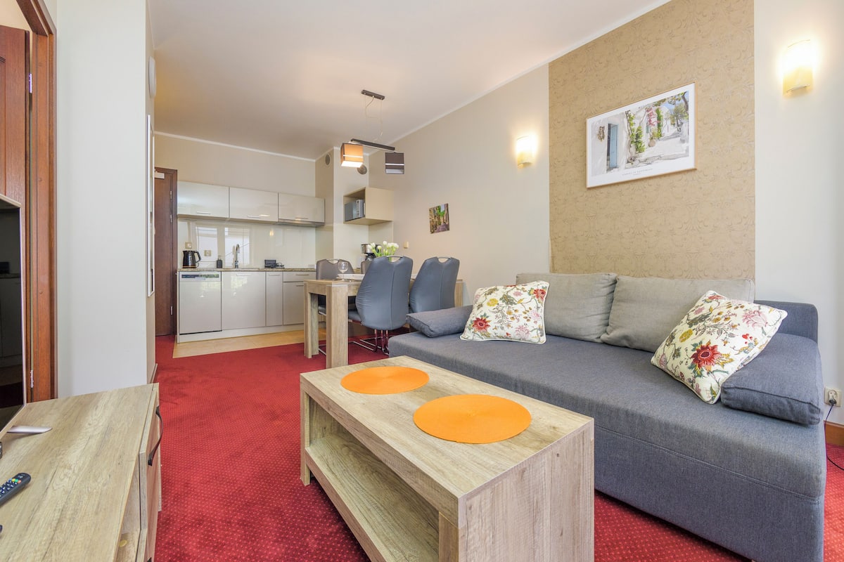 Un espacio habitable compacto con sofá, mesa de comedor y zona de cocina.