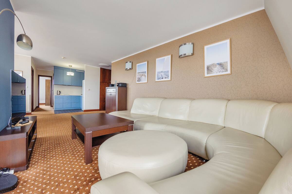 Una sala de estar moderna con un sofá grande en forma de L, una mesa de centro de madera y una alfombra estampada.