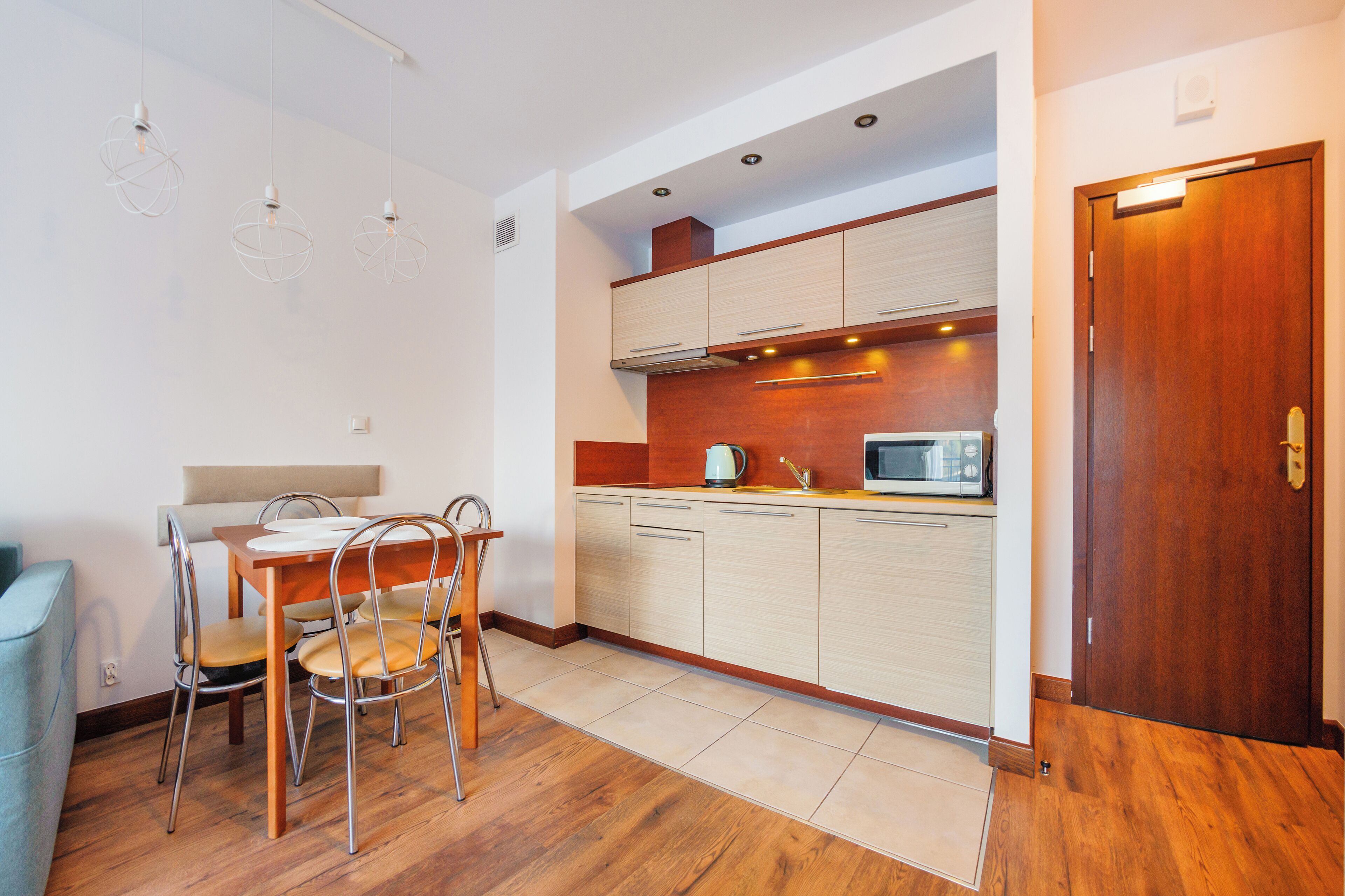 Une cuisine moderne avec des meubles en bois, un four à micro-ondes et un coin repas comprenant une table et des chaises.