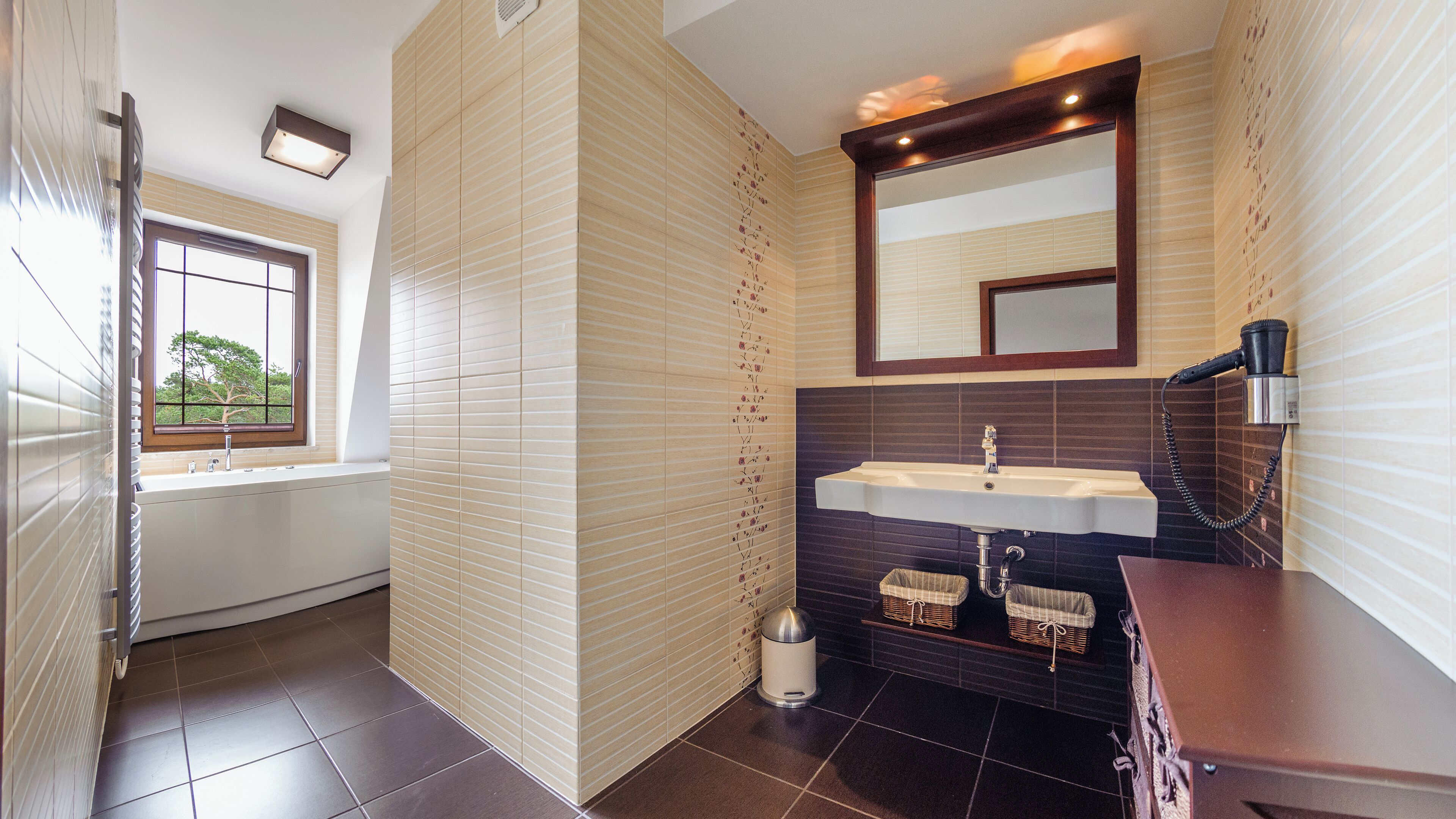 A bathroom with a window, a sink, a mirror, and a hairdryer.
