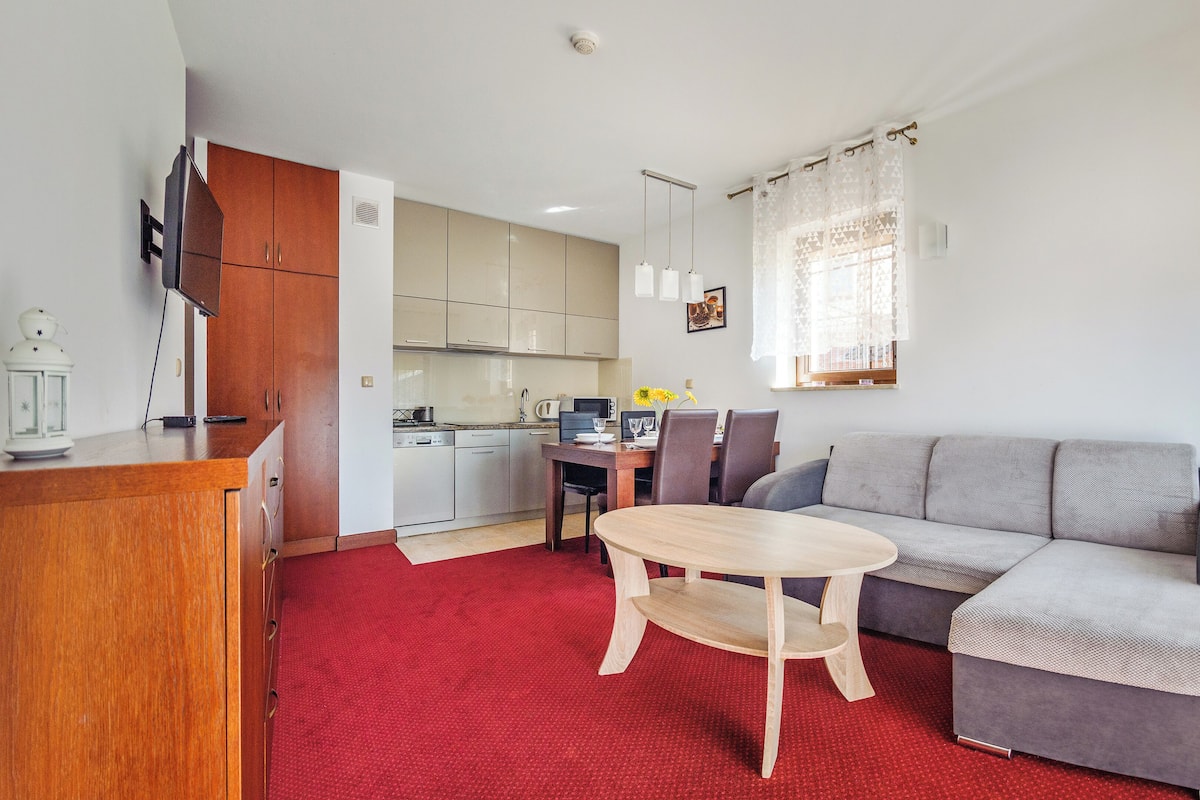Una sala de estar moderna con un sofá gris, una mesa de centro de madera y una alfombra roja.