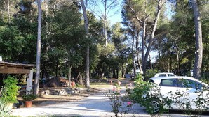 A campsite with tents, a white car, and a stone wall. - Les chambres Manon - Villa la Licorne (Belcodene)