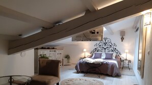 A bedroom with a bed, a chair, a round rug, and a small table. - Les chambres Manon - Villa la Licorne (Belcodene)