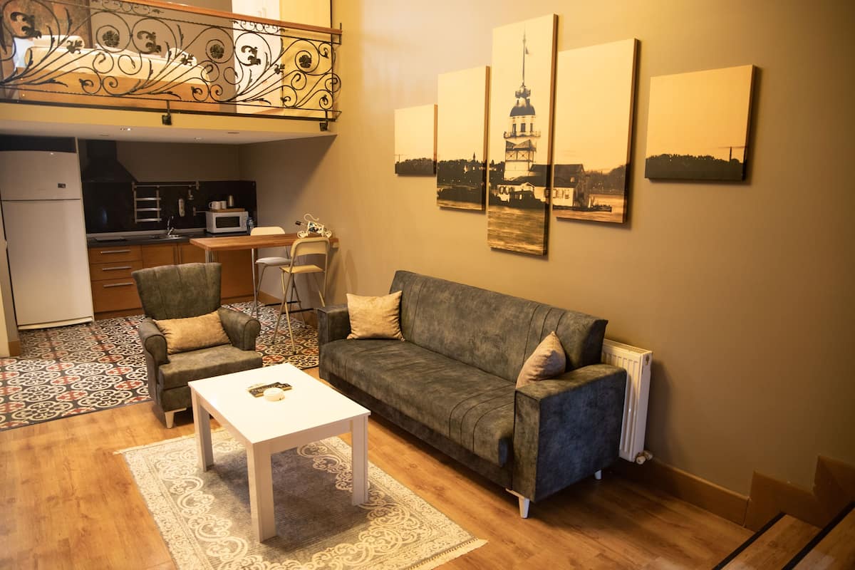 Un espacio habitable compacto con kitchenette, un sofá, una mesa de comedor y una mesita de centro.