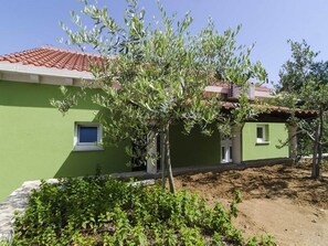 A green building with a tiled roof, a small window, and a door.