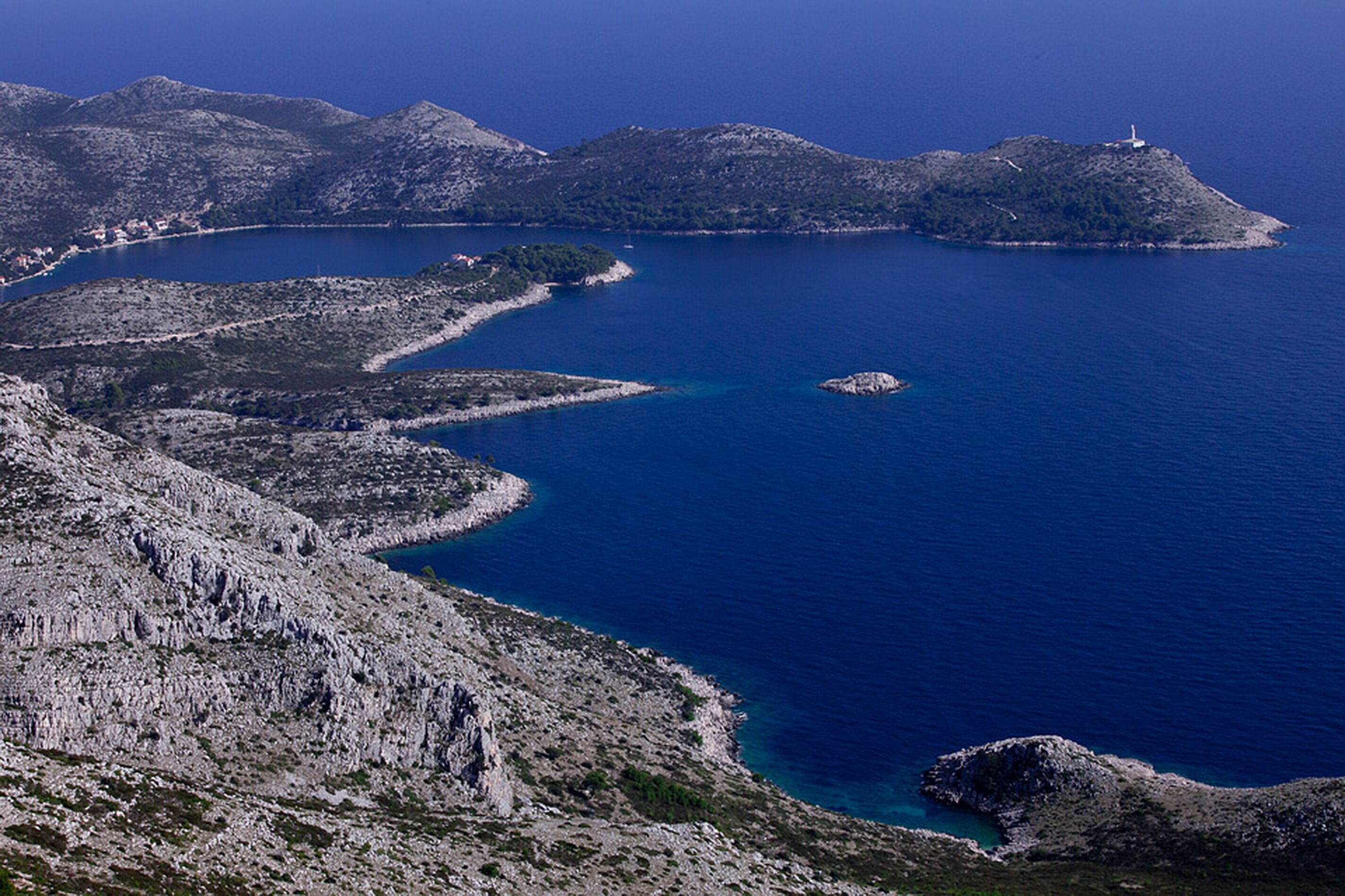 A rugged coastline with rocky terrain and a lighthouse on a small island.