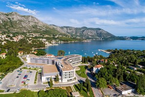 Vue aérienne d’une ville côtière, avec un bâtiment moderne à plusieurs étages et un parking.