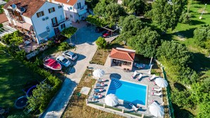 An aerial view of a property with a swimming pool, multiple cars, and a boat. - Apartments Mali Paradiso - One Bedroom Apartment with Terrace and Pool View (Mlini)