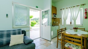 A room with a sofa, a dining table with chairs, a kitchen area, and a sliding glass door leading to an outdoor area. - Apartments Mali Paradiso - One Bedroom Apartment with Terrace and Pool View (Mlini)