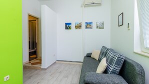 A living room with a grey sofa, a staircase, and a wall-mounted air conditioner. - Apartments Mali Paradiso - One Bedroom Apartment with Terrace and Pool View (Mlini)