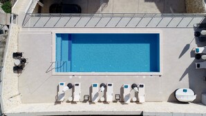 Una piscina en la azotea con superficie de agua azul cristalina, rodeada de sillas de descanso y una pequeña zona de estar.