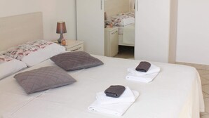 A neatly made bed with pillows and towels, a bedside lamp, and a wardrobe in a hotel room.
