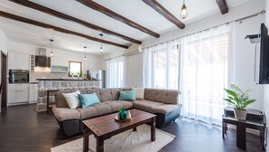 A modern living room with a sectional sofa, a wooden coffee table, and a kitchen in the background.