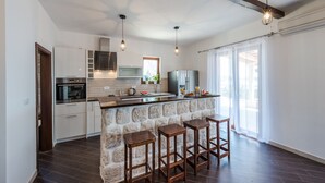 A modern kitchen with a stone island, bar stools, and a large window.