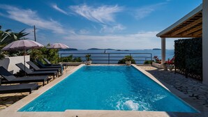 A rectangular swimming pool with a view of the sea and distant islands.