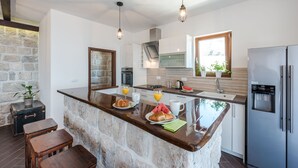 A modern kitchen with a stone island, stainless steel appliances, and a view of the outdoors.