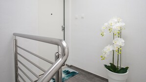 A staircase with a metal handrail, a white door, and a potted orchid plant. - Dva Galeba - Comfort One Bedroom Apartment with Sea View (205) (Bol)