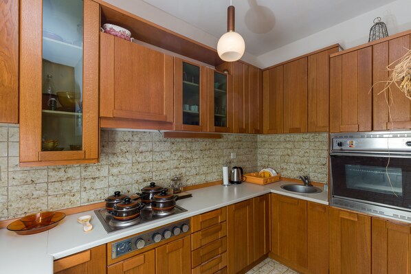 Une cuisine avec des meubles de rangement en bois, une cuisinière, un évier et un grand four.