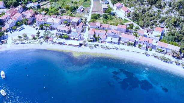 Vista aérea de un pueblo costero con edificios, una carretera y una playa.
