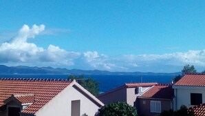 A coastal residential area with red-tiled roofs and a clear blue sky. - Apartments Mimose - Two Bedroom Apartment with Terrace and Sea View (Milna)